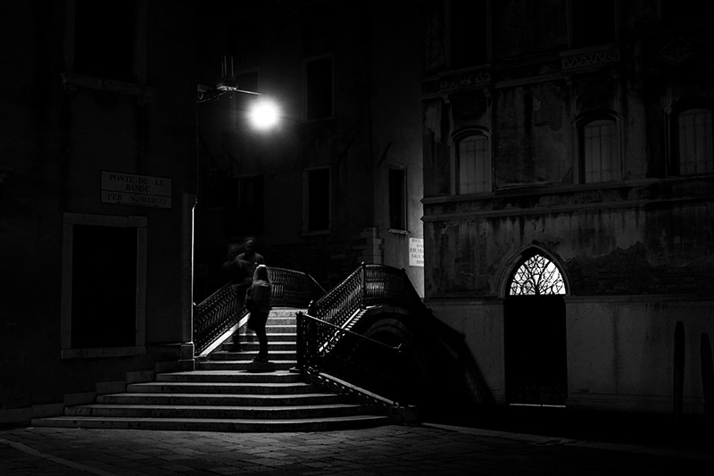 Pareja de noche bajo la farola de un puente veneciano